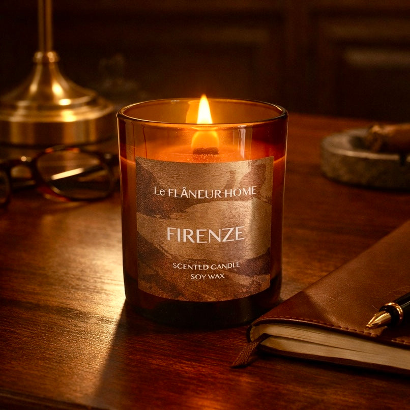 Candle labeled 'Firenze' by Le Flâneur Home on a wooden surface with a notebook and pen.