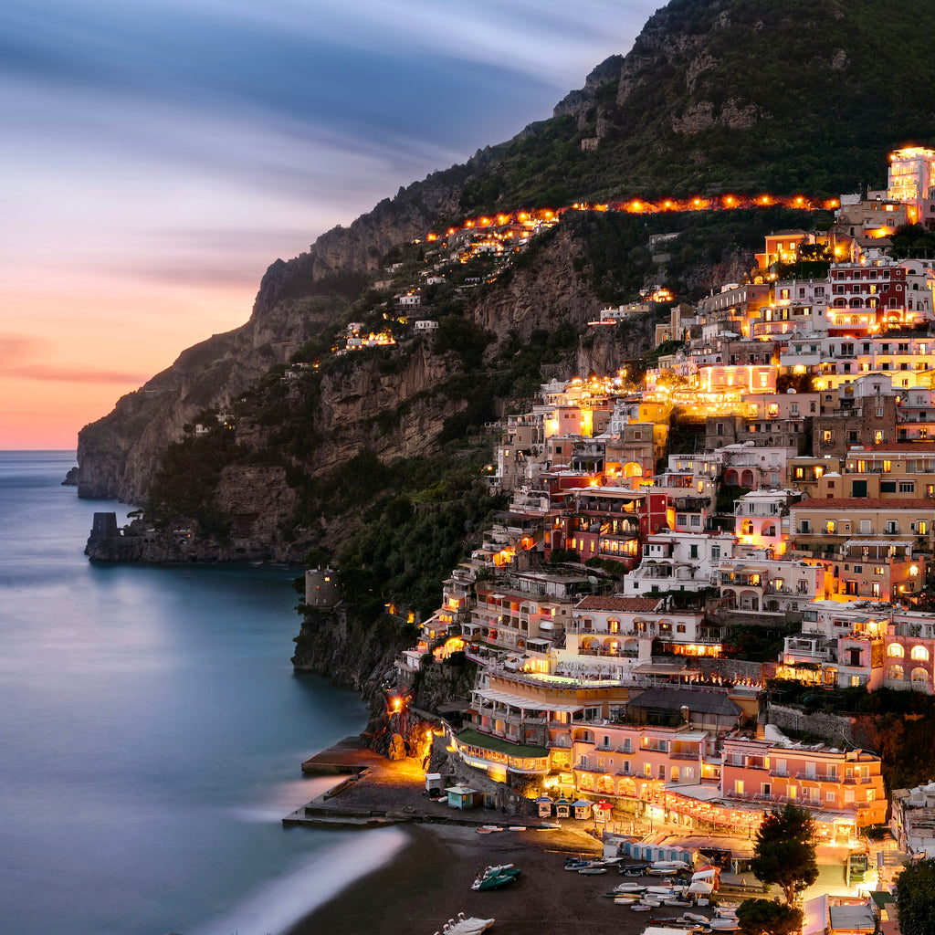 Positano with illuminated buildings on a hillside at dusk