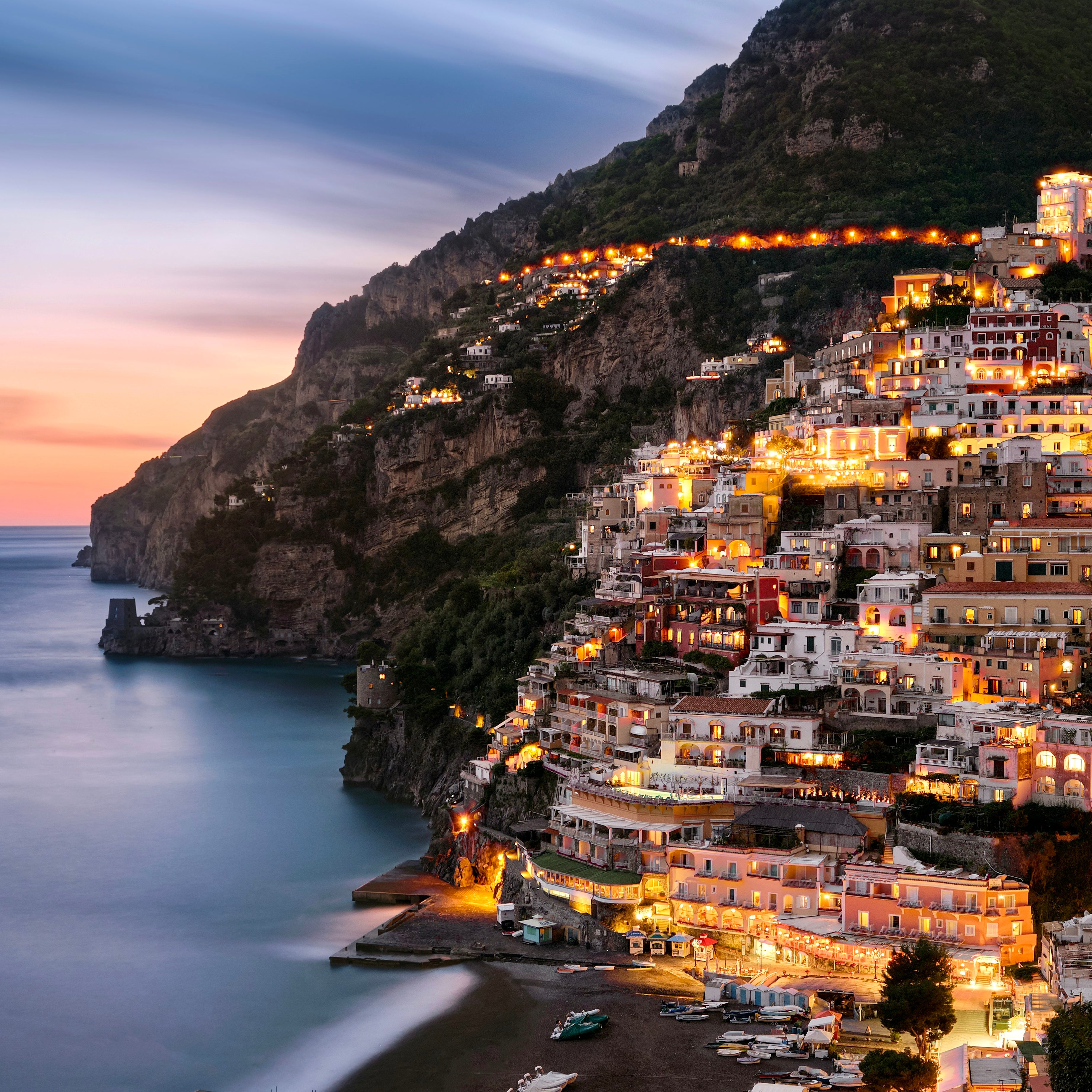 Positano with illuminated buildings on a hillside at dusk
