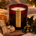 Le Flâneur Home Festive Memories scented candle in red glass with a wooden wick, styled with dried orange and holly.